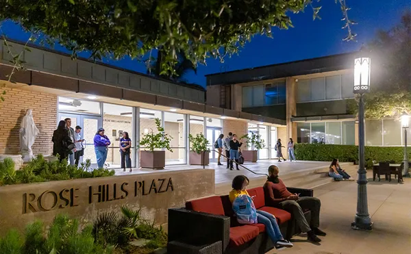 Students sitting on a bench in front of a low building at night