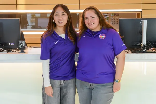 two female students smiling at the front desk of the wellness pavilion