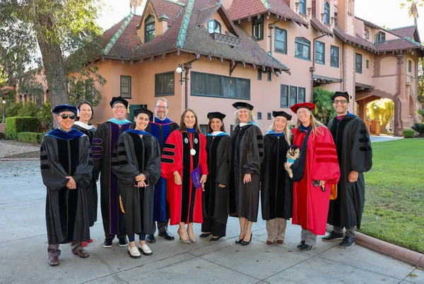 President Ann with faculty members smiling in front of the Doheny mansion