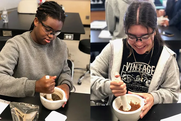 Two students sitting at benches doing lab work