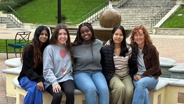 A group of students sitting with Luiza Nogaj sitting near a fountain