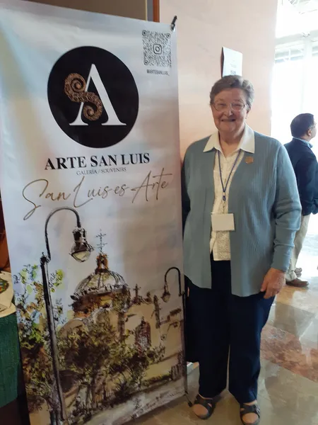 A woman standing next to a banner of Arte San Luis