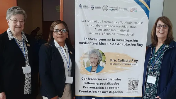 Three woman standing next to a conference banner