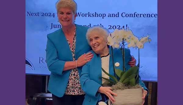 Two women posing on stage at the Roy Adaptation Association conference