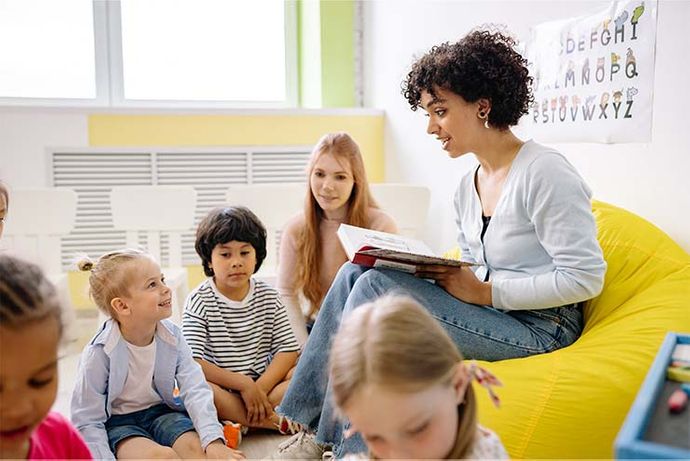 young teacher reading a book to a group of kids