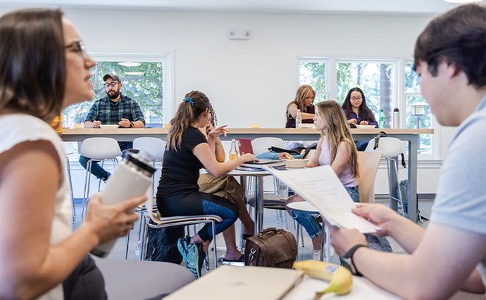 students sitting on campus at various tables chatting