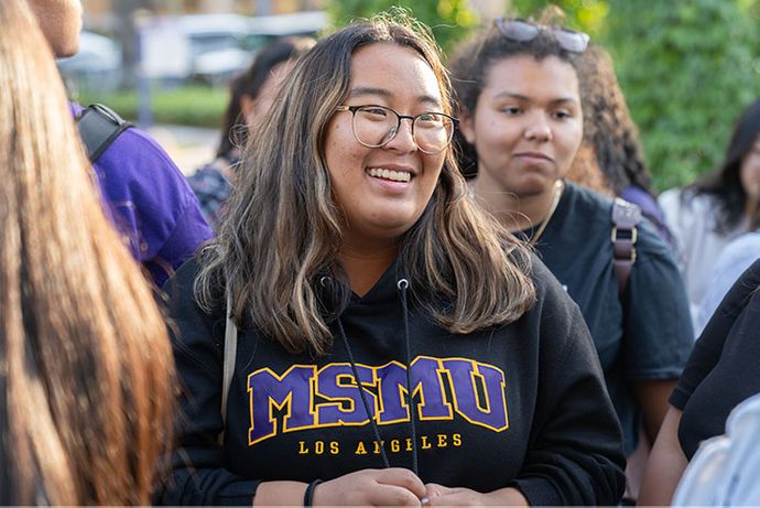 student smiling talking to someone with a 91ɬ�� sweater on
