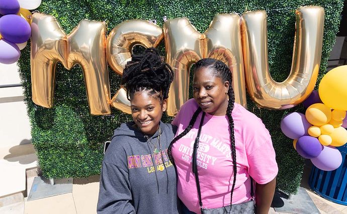 two students smiling in front of 91ɬ�� balloons