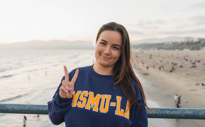 A 91ɬ�� student giving a peace sign on the LA Pier