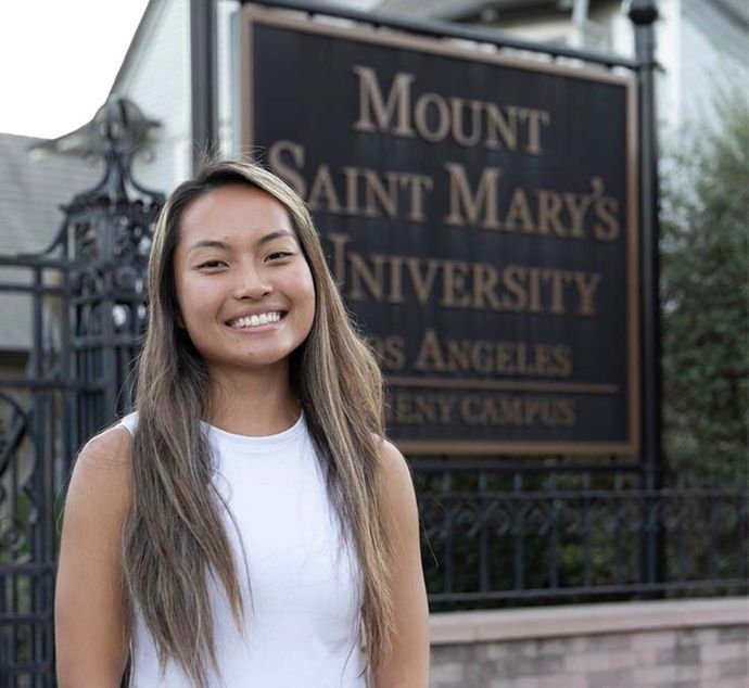 female student smiling in front of 91ɬ�� campus sign