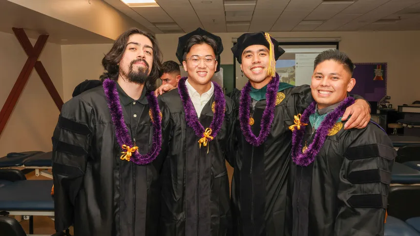 four DPT graduates in robes smiling