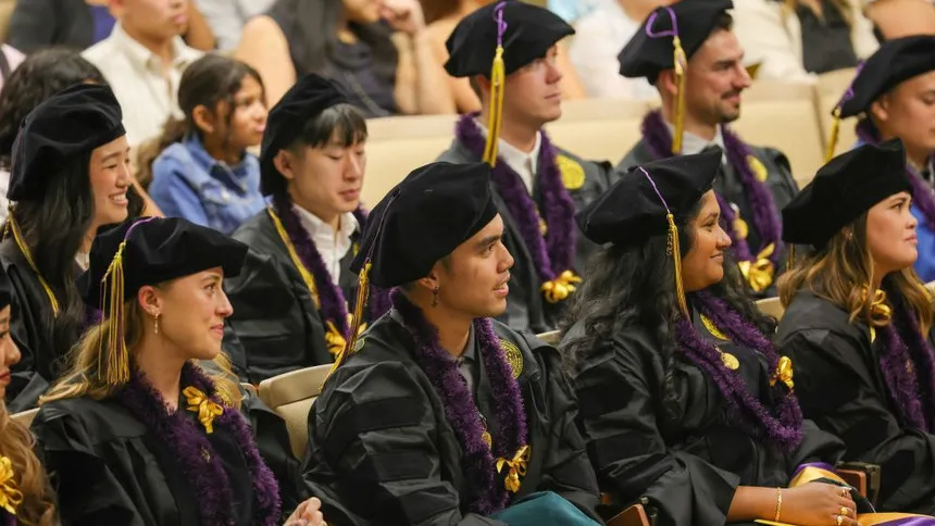 DPT graduates in robes sitting in an auditorium during the graduate ceremony
