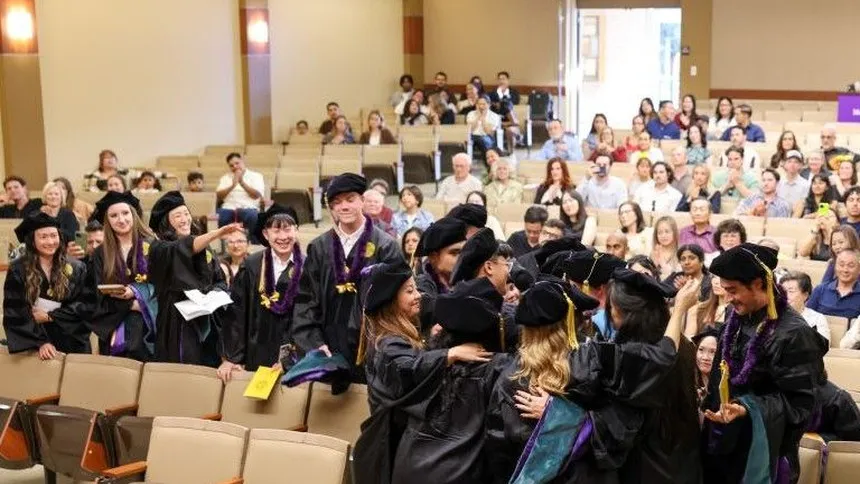 DPT Graduates embracing in an auditorium during the graduation ceremony