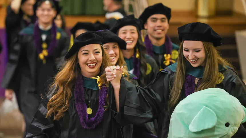 DPT Graduates walking out of an auditorium smiling